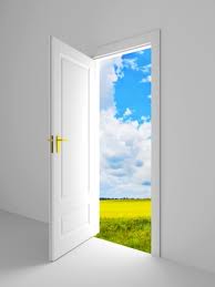 Picture of white door ajar, and beyond door is a meadow and blue sky.