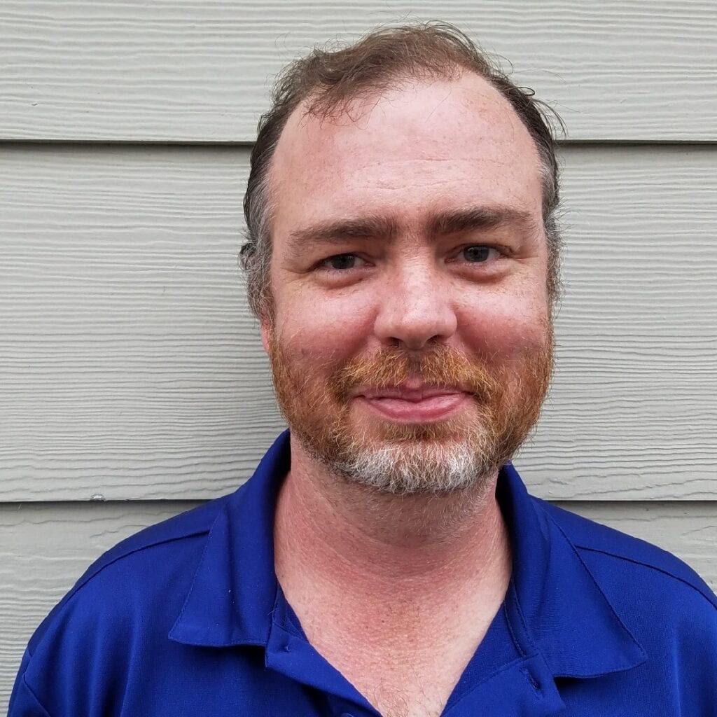 Picture of Matthew Colvin, wearing blue shirt with a beige background.  Caucasian male with brown hair and blue eyes.